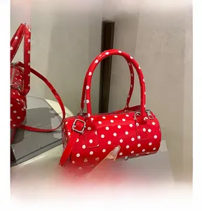 Macro detail of red polka dot cylinder bag with glossy finish and silver metal zipper