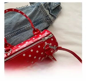 Close-up of red polka dot cylinder bag featuring silver zipper and red handle details