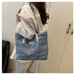 Close-up of blue denim tote bag with silver glitter finish on a female model