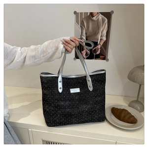 Close-up of black tote bag featuring silver polka dots and metallic silver leather handles