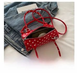 Internal view of red polka dot cylinder bag showing phone, wallet and mirror storage