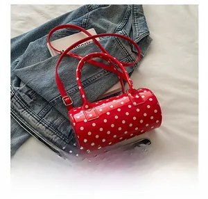 Detail view of red polka dot mini cylinder bag with smartphone for size comparison