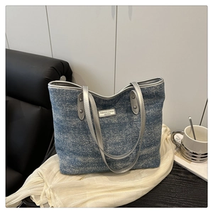 Detail of blue denim textured tote bag with silver glitter fabric and metallic handles