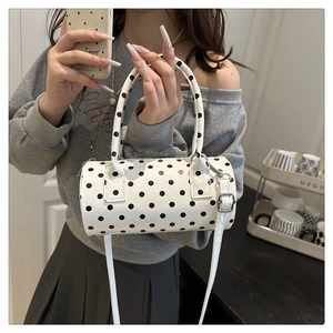 Close-up of a white polka dot barrel bag featuring black dots and a detachable shoulder strap