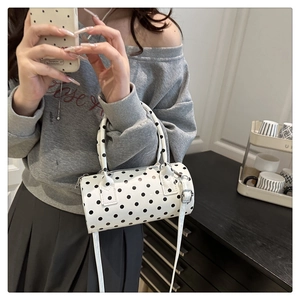 Close-up of polka dot cylinder bag with top handle and silver hardware detail
