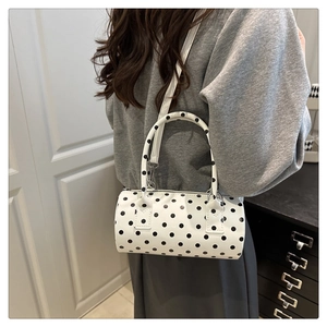 Polka dot cylinder bag with dual handles and detachable shoulder strap on model