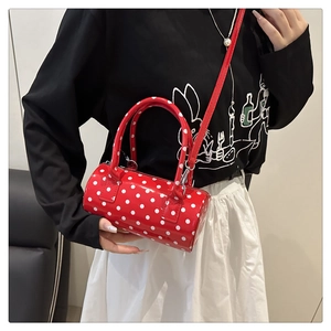 Polished red cylindrical Boston bag with white polka dots shown on a model