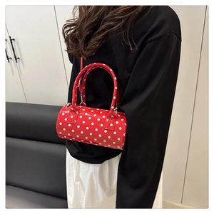 Close-up of red polka dot cylinder bag worn cross-body to show size and scale