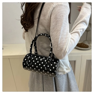 Polka dot boston bag shown on model with shoulder strap in a cozy indoor setting