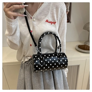 Close-up of a stylish black polka dot cylinder handbag with metallic silver hardware details