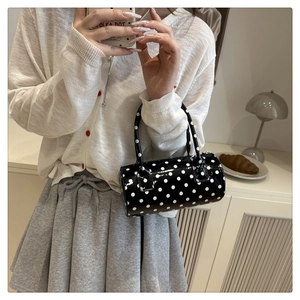 Close-up of polka dot cylindrical handbag with glossy finish and slim handles