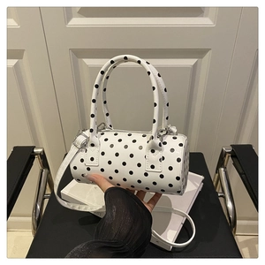 Close-up of a stylish white cylinder handbag with black polka dots and shiny silver zipper