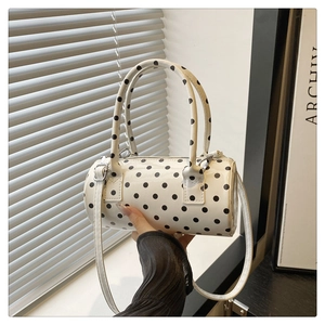Detailed view of white polka dot cylinder handbag with metallic hardware and zipper