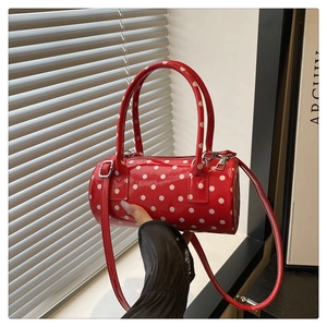 Detailed view of red polka dot cylinder handbag with glossy finish and silver hardware