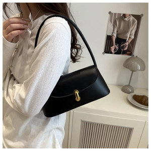 Close-up of minimalist black leather shoulder bag with elegant gold metal twist lock