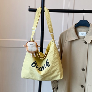 Yellow nylon canvas tote bag with Beach print and plush bread charm on a hanger