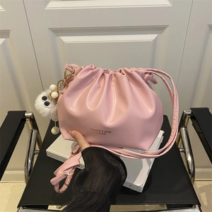 Pink pleated leather bucket bag with drawstring and white plush monster charm accessory
