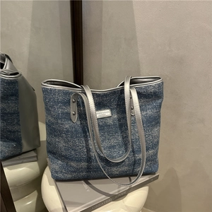 Retro blue denim tote bag with silver leather trim and metal logo plate shown in mirror