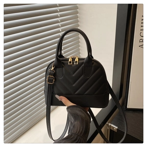 Detalle de bolso tipo concha negro acolchado en V con cremalleras doradas y asa