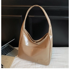 Close-up of a large coffee-colored patent leather tote bag with glossy finish and magnetic clasp