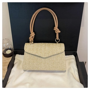 Détail du sac à main en paille tressée avec poignée nouée et texture en V élégante
