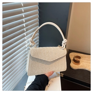 Détail du tissage en V sur le sac crème avec chaîne dorée et poignée à nœuds élégante