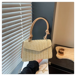 Vue détaillée du sac tissé beige avec poignée en cuir et fine bandoulière en chaîne dorée