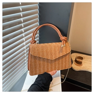 Détail du sac bandoulière en paille tressée avec poignée cuir et bandoulière chaîne