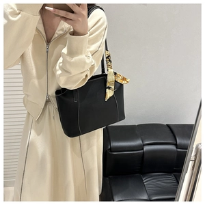 Detail of black leather tote bag with white contrast stitching and printed silk scarf handle