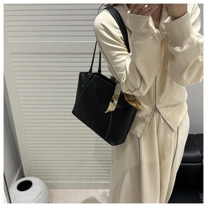 Black leather tote bag with white contrast stitching and silk scarf on the shoulder strap