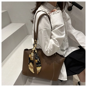 Close-up of brown PU leather tote bag with white stitching and retro silk scarf handle