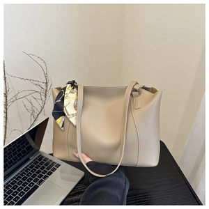 Detail of khaki tote bag with matte finish and geometric scarf decoration on handle
