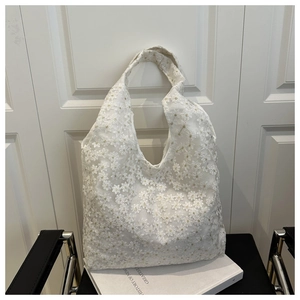 Detail of white lace tote bag featuring elegant floral embroidery and mesh design