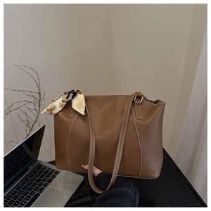 Close-up of caramel leather tote bag with elegant vintage silk scarf on a desk