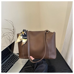 Detail of brown faux leather tote bag with white contrast stitching and silk scarf accessory