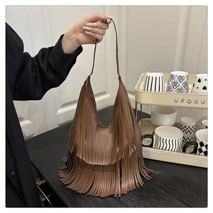 Detail einer dunkelbraunen Ledertasche mit langen Bohème-Fransen und Schultergurt