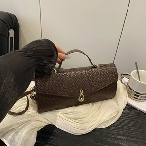 Brown woven leather shoulder bag with gold hardware on elegant white fabric