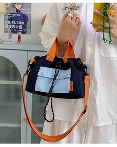 Close-up of contrast nylon crossbody bag with drawstring closure and orange handles