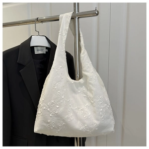 Vue détaillée du sac cabas en coton blanc avec broderie florale élégante et bandoulière
