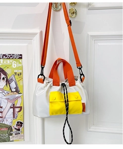 Detailed view of bicolor nylon crossbody bag with orange handle and yellow pocket