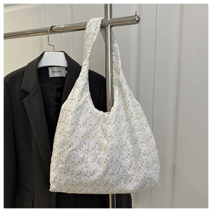 Détail du sac cabas en tissu crème avec broderie florale jaune et motifs ajourés
