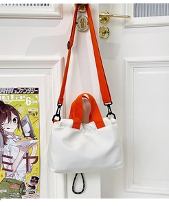 Detail of white nylon crossbody bag featuring contrast orange straps and adjustable handle