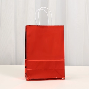 Close-up of shiny red metallic gift bag featuring white twisted paper rope handles