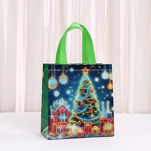 Christmas non-woven gift bag with luminous tree pattern and green handles on white surface