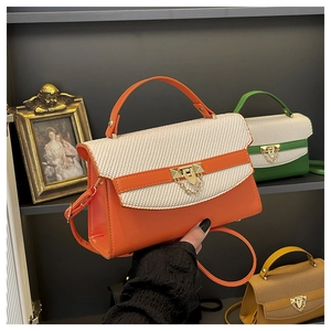 Dettaglio borsa Kelly bicolore con patta intrecciata e chiusura a triangolo oro