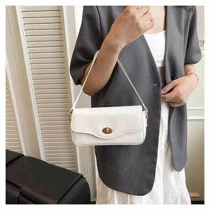 Minimalistische weiße Ledertasche mit Goldschloss am Model im grauen Anzug gezeigt