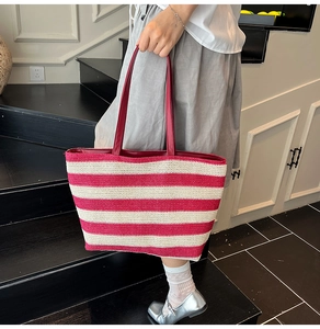 Fashionable red and white striped woven tote bag with leather handles shown by model