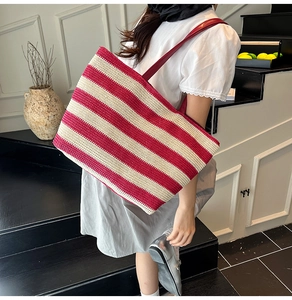 Détail du sac cabas en paille à rayures rouges et blanches avec anses en simili cuir rouge