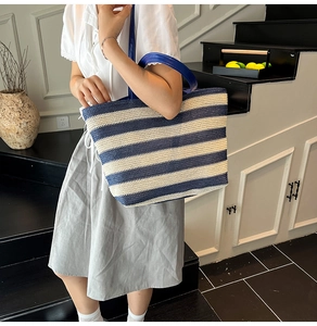 Gros plan du sac cabas en paille à rayures bleues et blanches avec anses en cuir