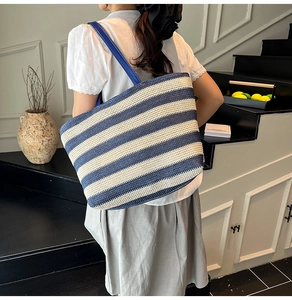 Détail du grand sac cabas tissé à rayures bleues et blanches porté à l'épaule avec style